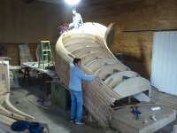 Lengths of solid bent oak that are 1 inch square are strip planked to form the hull. Later, this will be ground smooth and faired out like a yacht hull
